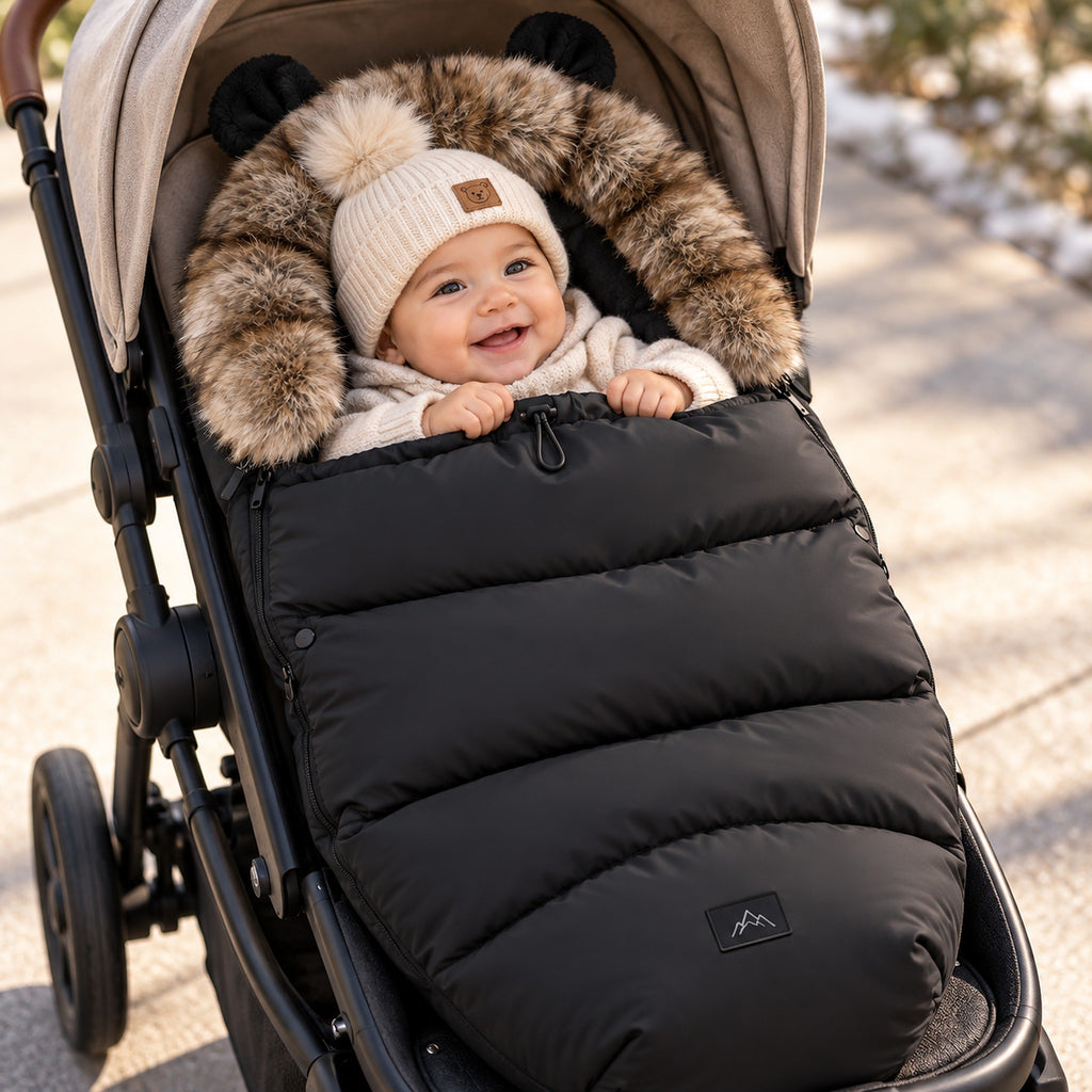 Bébé souriant au chaud dans une chancelière poussette noire doublée de polaire