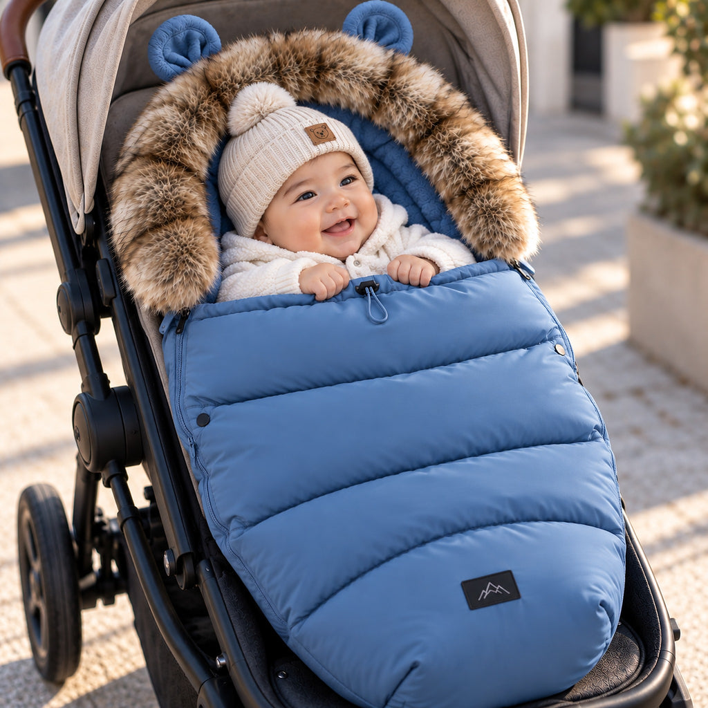 Bébé bien emmitouflé dans une chancelière poussette bleue coupe-vent en balade